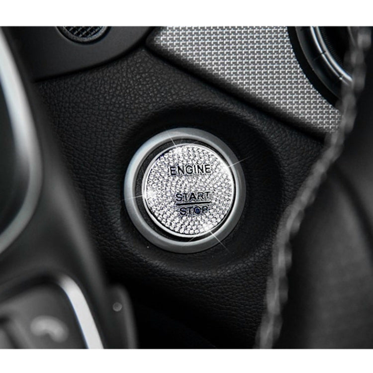 Round silver rhinestone engine start/stop button cover on dark dashboard