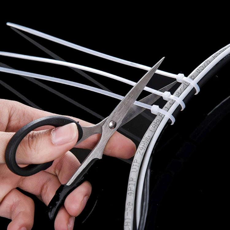 Black nylon cable ties being trimmed with scissors at the locking end