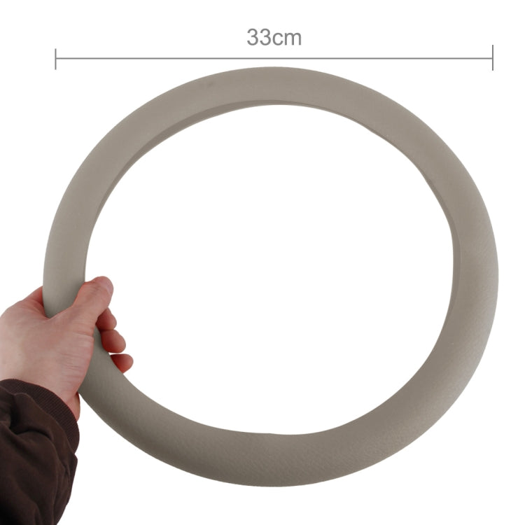 Grey rubber steering wheel cover, circular loop with hand holding at the edge