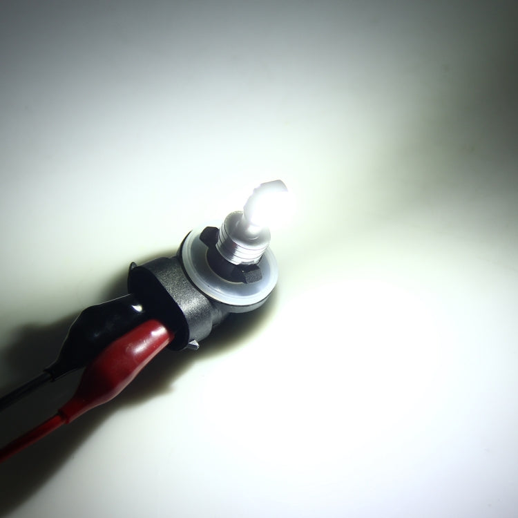 Car fog light LED bulb emitting bright white light in a dark setting