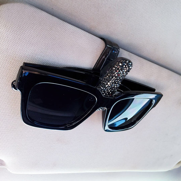Black glasses bill clip holder with rhinestone-covered band, holding black sunglasses