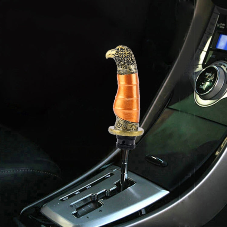 Black gear shift knob with gold eagle head and orange band, eagle beak topper