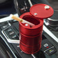 Red metal portable car trash bin/ashtray with open lid and cigarette resting inside