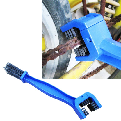 Blue chain cleaning brush with black nylon bristles, scrubbing a motorcycle chain near wheel