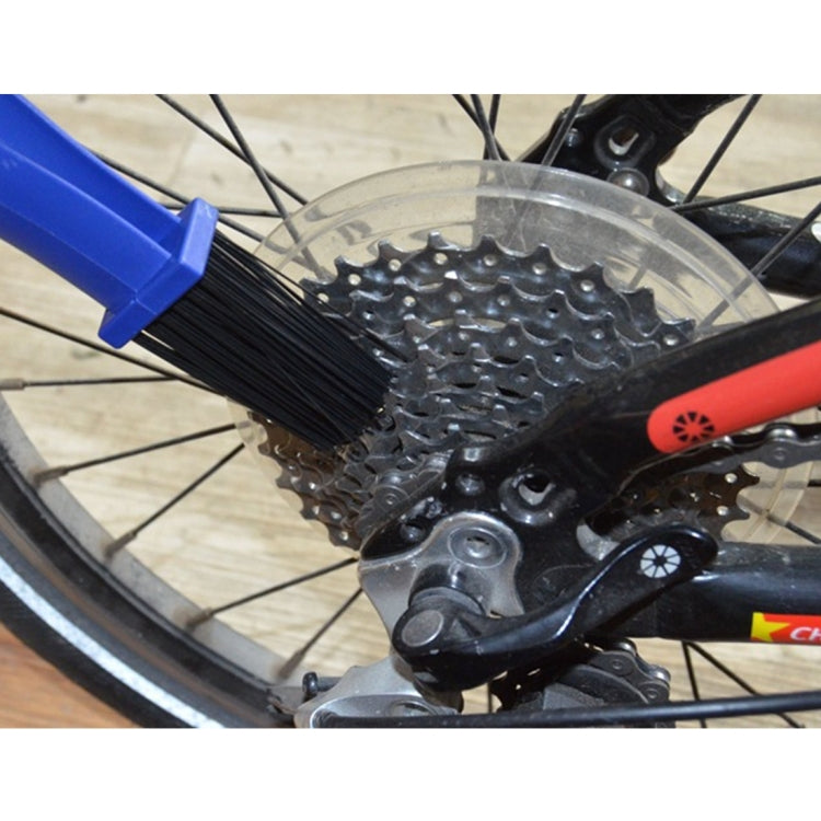 Blue brush bristles cleaning a bicycle chain and sprocket on a wheel