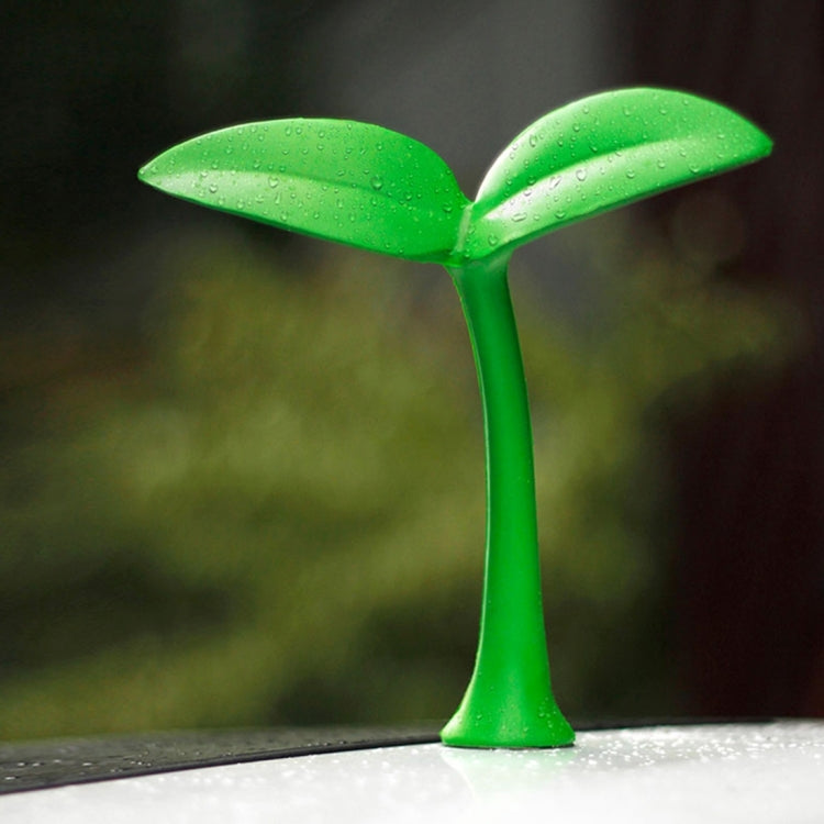 Green rubber decorative grass topper standing on car hood with droplet texture