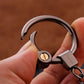 Metal car keychain holder held in hand with chrome ring and black metal car charm.