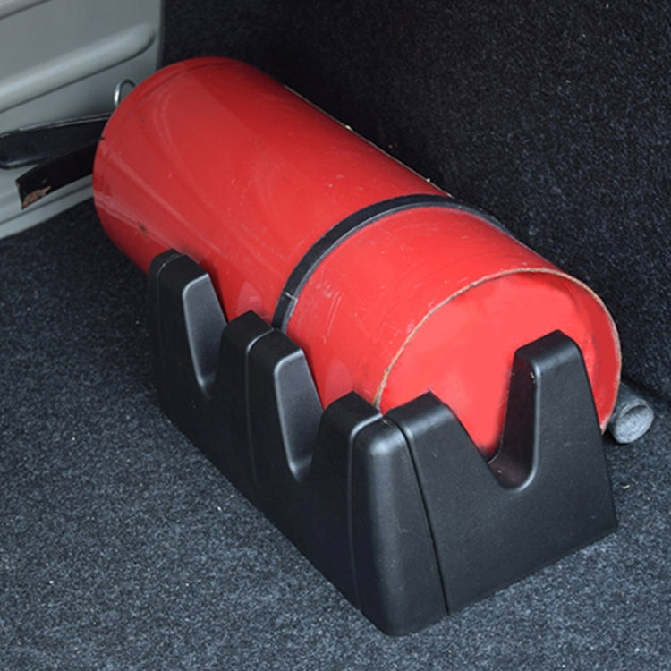Black plastic vehicle holder gripping a red cylindrical item on a floor surface