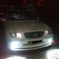 Front view of a car with bright white headlight beams from LED bulbs at night.