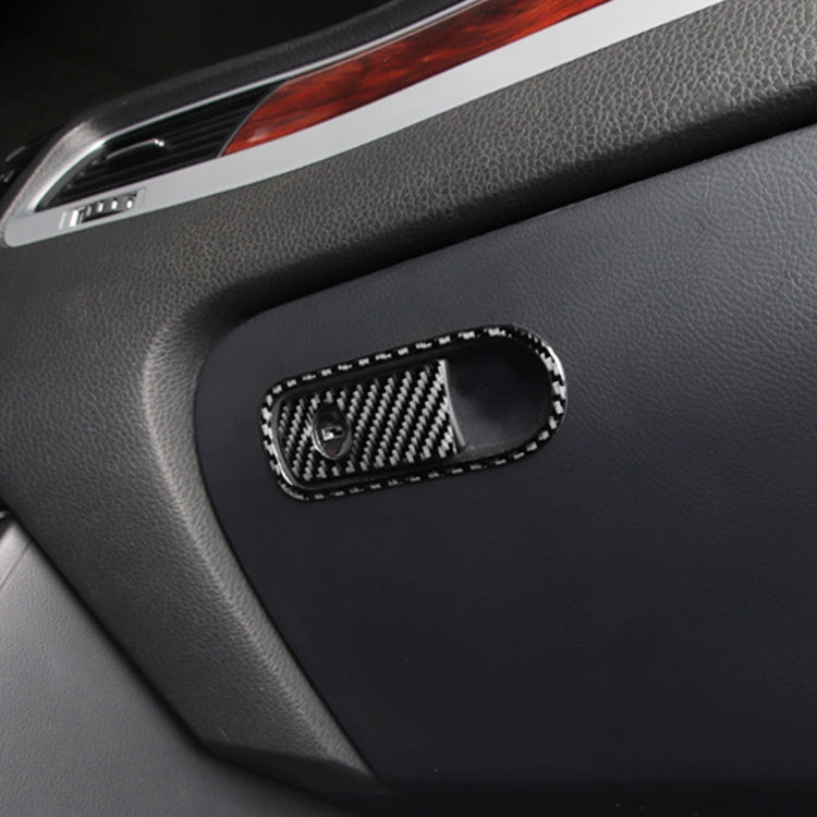 Carbon fiber-pattern switch bezel on car armrest panel with oval frame and circular cutout