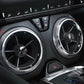 Four round carbon-fiber style air vent stickers on car dashboard vents