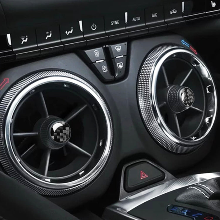 Four round carbon-fiber style air vent stickers on car dashboard vents