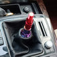 Red threaded gear shift knob adapter installed in a car shifter boot