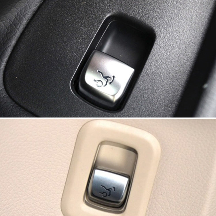 Trunk release switch button in black and beige trim, metallic housing with icon