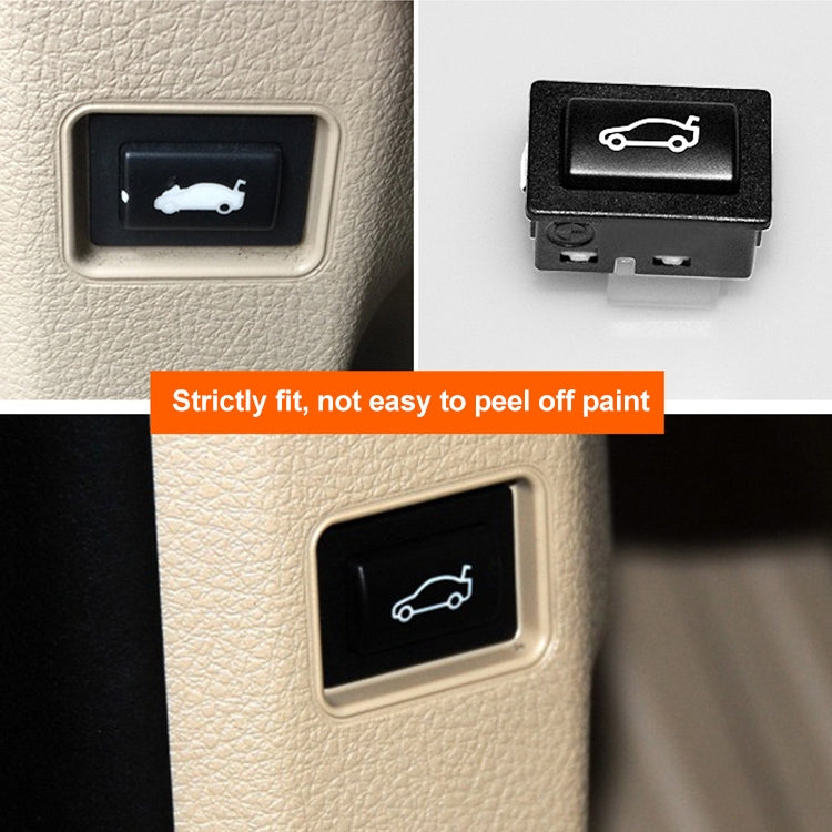 Car trunk switch button installed in beige dashboard panel, black bezel and white icon