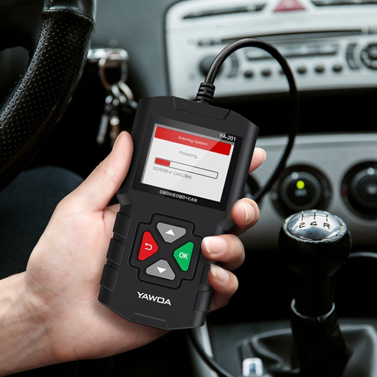 Black handheld OBD2 diagnostic code reader with lit screen held near car dashboard
