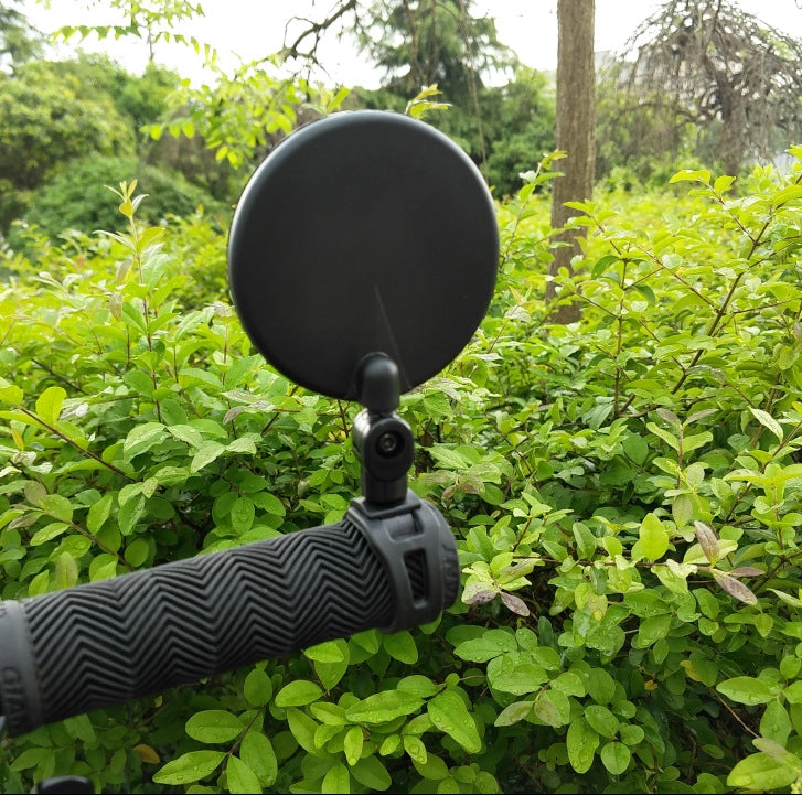 Bicycle rearview convex mirror attached to handlebar with black mounting arm.