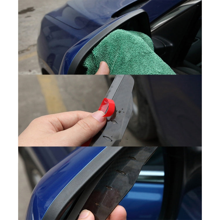 Hand applying black rearview mirror rain blade to car side mirror