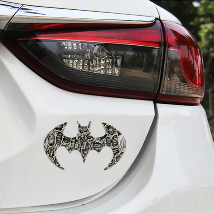 Bat-shaped metal car sticker with lighter, textured carbon-fiber bat icon on car body