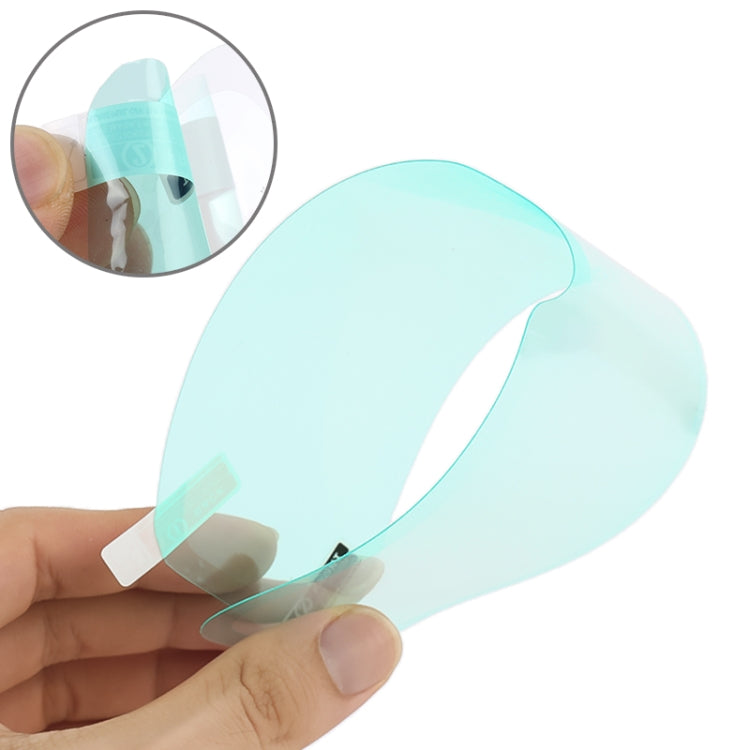 Motorcycle helmet visor anti-fog film held in hands, transparent mint tint