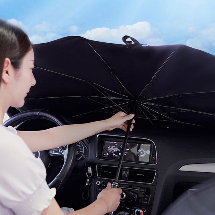 Car windshield sunshade, dark umbrella-style cover being fitted from the driver seat.