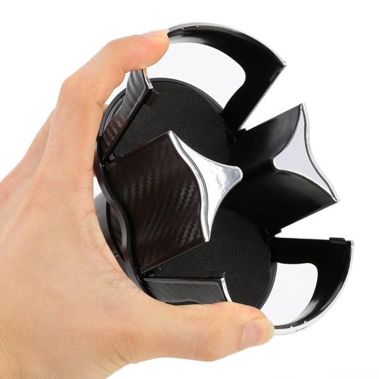 Black car cup holder held open by hand, showing dual cup compartments