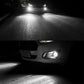 Vehicle fog lights glowing white, casting a beam onto the road