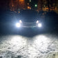 Car front with white fog lights on, illuminating snowy road surface