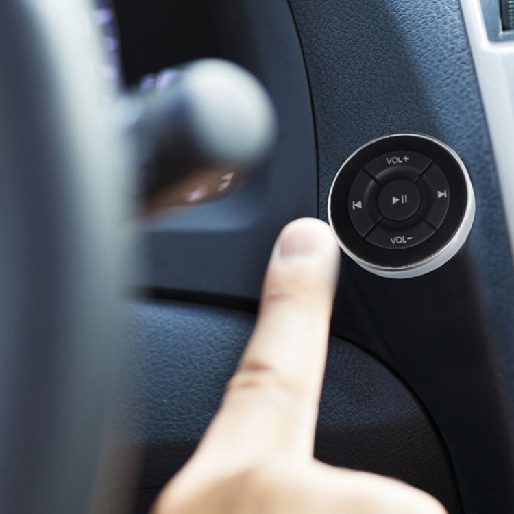 Mounted car Bluetooth remote on dashboard, finger pressing center play/pause button