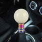 Beige/cream acrylic gear shift knob with smooth globe head and rainbow base.