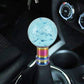 Light blue acrylic gear shift knob with bubble-like texture and rainbow metal stem.