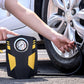 Portable 12V tire inflator pump with gauge, yellow-and-black body, connected to a car tire