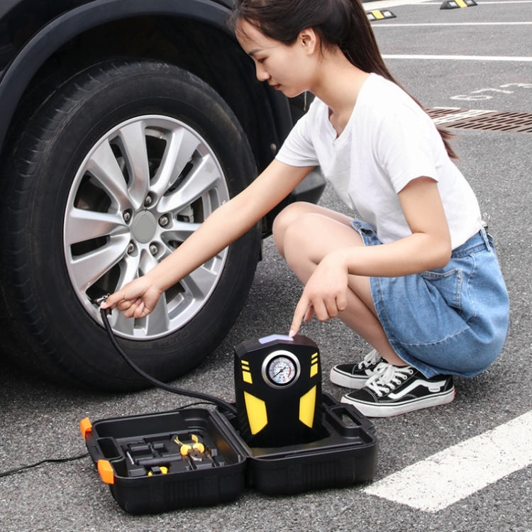 Person kneeling by car tire using 12V air pump with pressure gauge and tool box