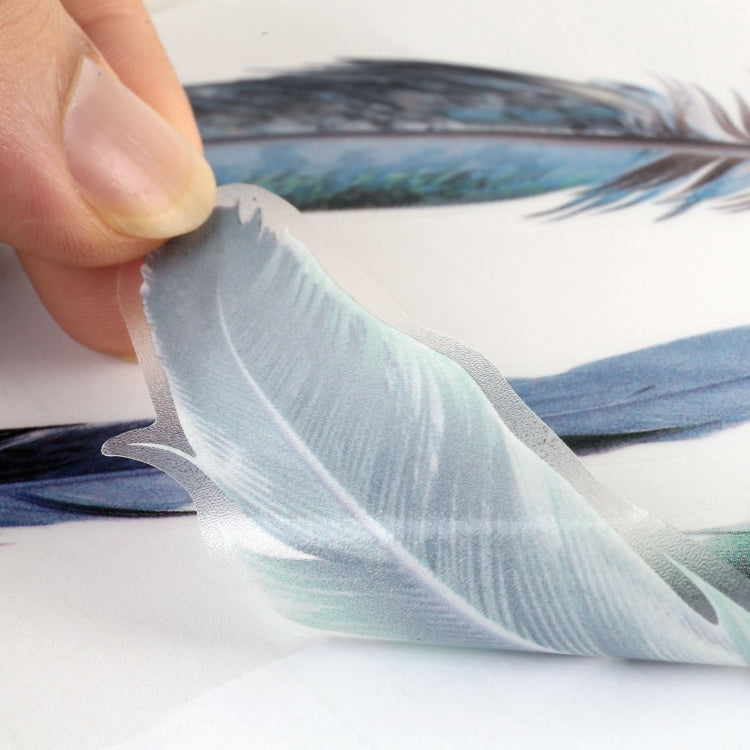 Hand applying a blue-gray feather car sticker on a white car panel