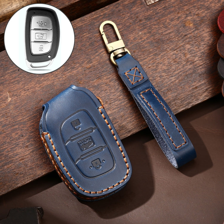Blue leather key fob cover with stitched trim, brass key ring, and remote button cutouts