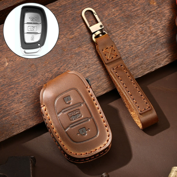 Brown leather key fob cover with stitched trim, brass key ring, and remote button cutouts