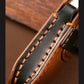 Close-up of black leather key cover strap with orange stitched seam and metal clip
