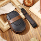 Black leather key fob case with wrist strap and decorative contrast stitching.