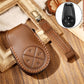 Brown leather key fob cover with circular button design and key strap.