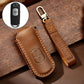 Brown leather key case with button cutout, key ring loop, and tan edge stitching