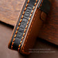 Black leather key case strap with orange stitched edges and embossed button icons