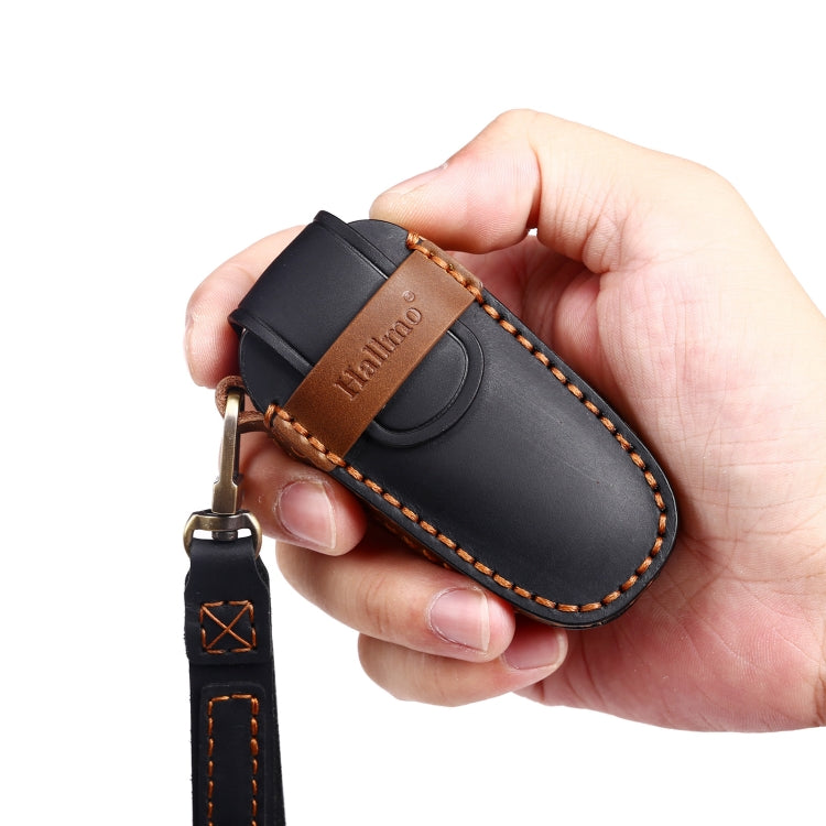 Black leather key fob protective cover held in hand with brown stitched trim