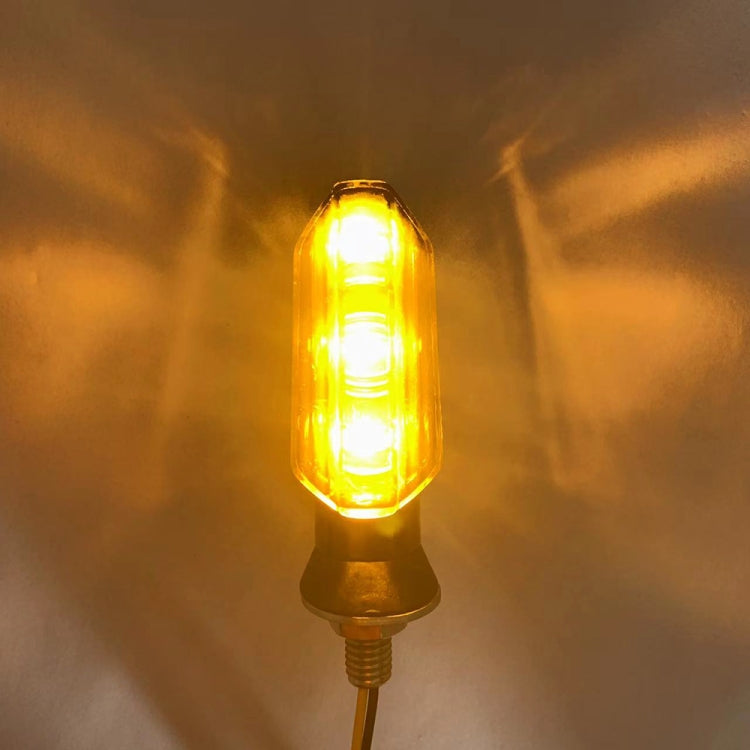 Amber motorcycle LED turn signal light glowing, clear lens on threaded base