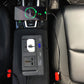 Car dashboard setup with inverter plugged into outlet and blue display reading 14.2