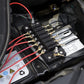 Close-up of black fuse terminal block with red and black wires on screw terminals