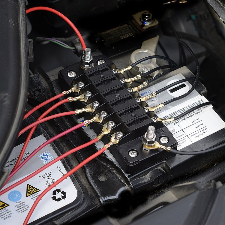 Close-up of black fuse terminal block with red and black wires on screw terminals