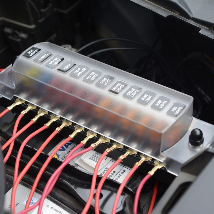 Silver fuse box terminal module with black knobs and connected red wiring to brass terminals