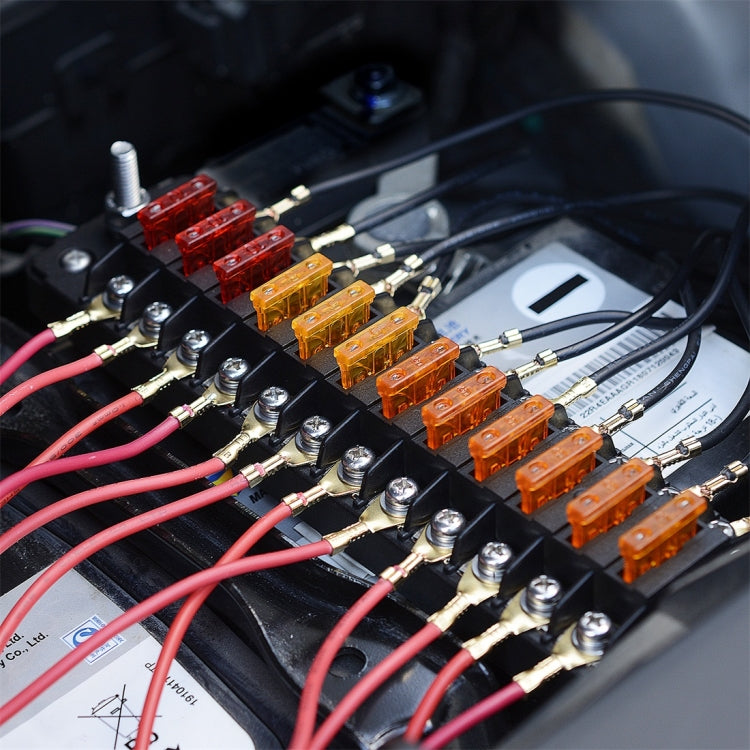 Automotive fuse box installed with colored blade fuses and connected ring terminals on wires