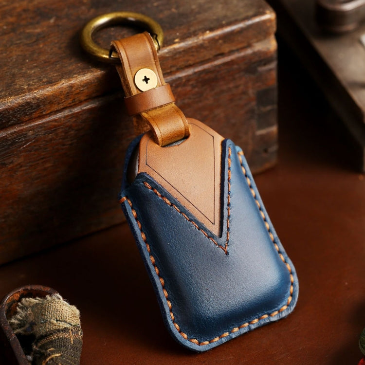 Tan and blue leather key fob cover with metal ring loop and stitched chevron panel.