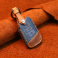 Blue leather key cover with brown trim, metal ring, stitched edges, and button panel